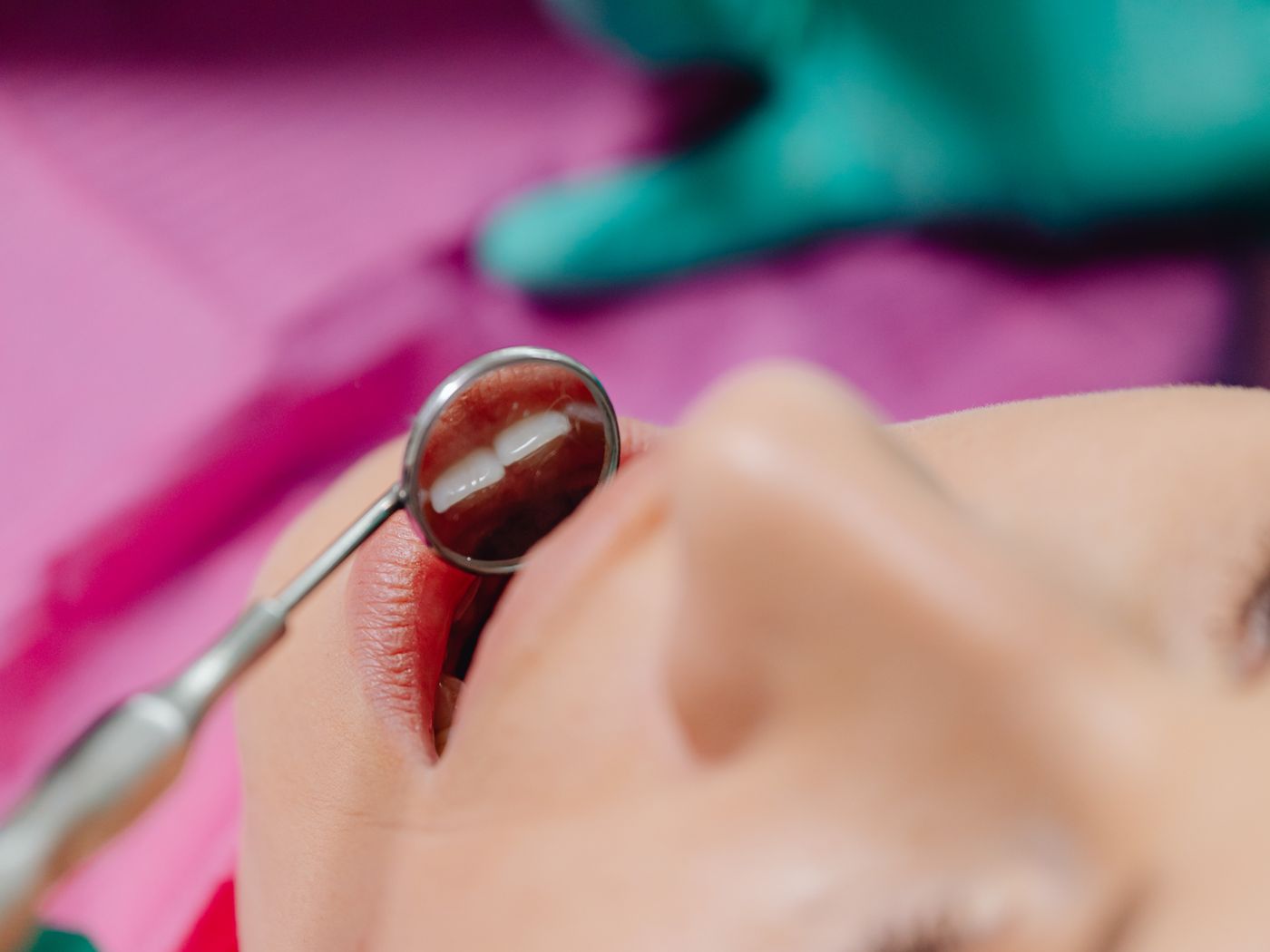 Dentist in scrubs speaking with a seated patient during a routine dental examination