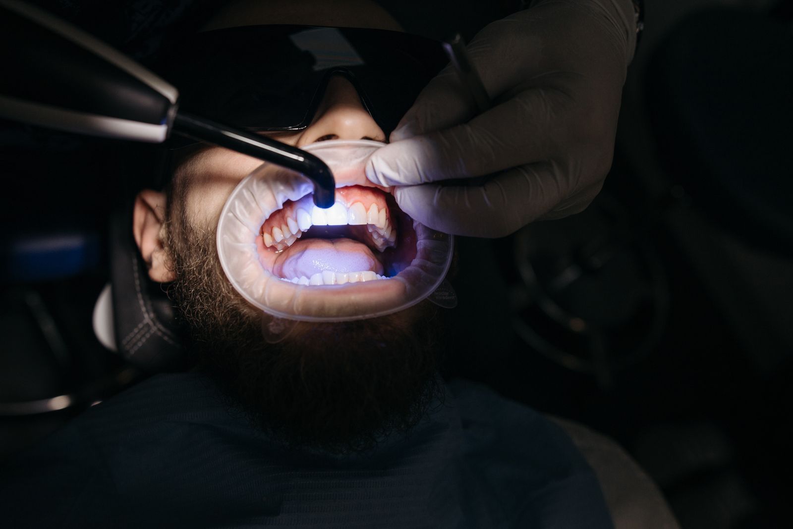 Dentist using a focused light-based dental device on a patient's teeth