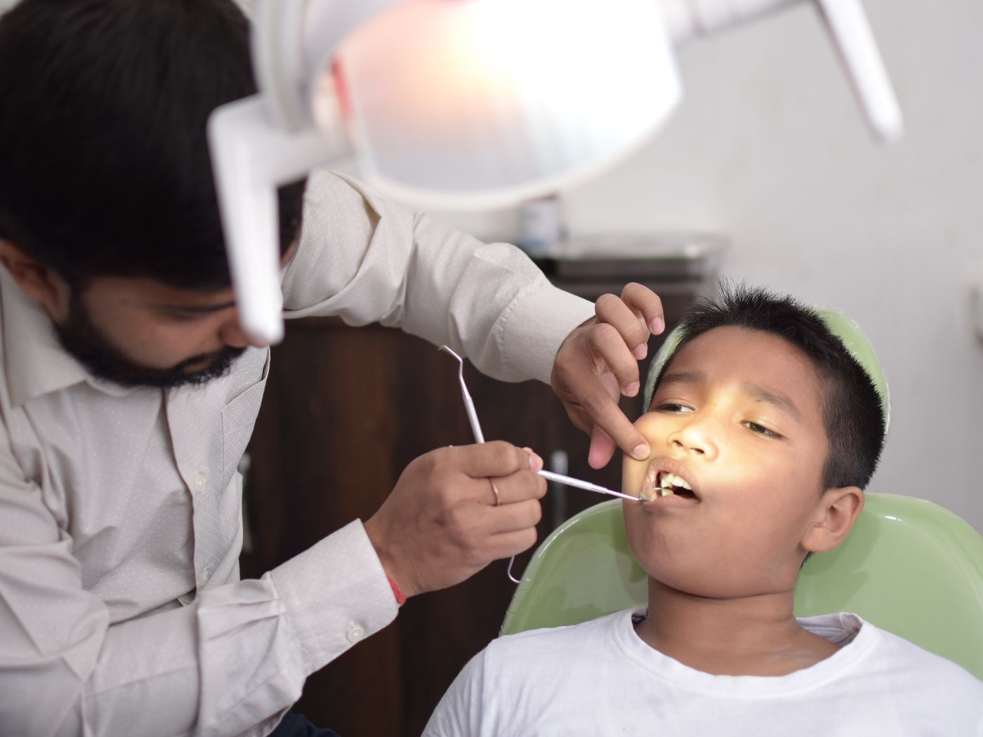A smiling child seated in a dental chair with a friendly dental professional